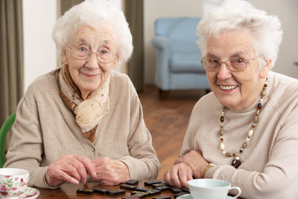 Two Senior Women Playing Dominoes At Day Care Centre